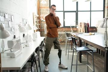 Sticker - Young serious fashion designer or tailor with prosthesis instead of one leg standing in workshop