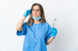 © luismolinero - Woman Romanian dentist holding tools over isolated on pink background having doubts and thinking