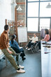 © pressmaster - Young female creative designer in wheelchair pointing at sketch on whiteboard at seminar