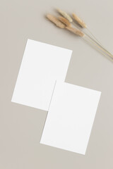 Sticker - Two white invitation cards mockup with a lagurus decoration on the beige table. 5x7 ratio, similar to A6, A5.