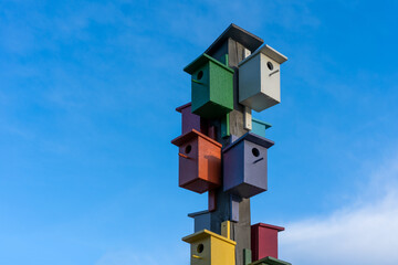 Pillar with colorful birdhouses against the blue sky