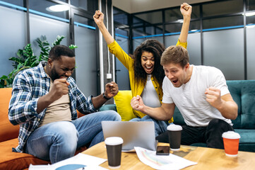 Overjoyed employees or students feeling euphoric in office, looking at the laptop screen, screaming. Excited male and female passing important exams or get a big profit from corporate project