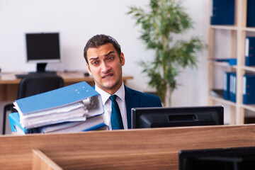 Young male employee unhappy with excessive work in the office