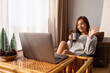 © Farknot Architect - A beautiful young asian woman using laptop computer for video call while sitting and drinking coffee at home