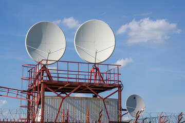 Satellite dish antenna on top of the building close-up against the blue sky.