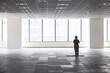 © Marlon Hutajulu - Silhouette photo of a janitor woman cleaning a hall inside a building with large windows with sun light background at the big window.