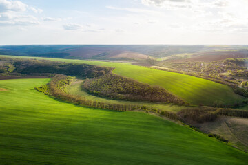 Wall Mural - aerial view of beautiful countryside with green rolling field in golden hour before sunset