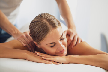 Professional masseur doing therapeutic massage. Woman enjoying massage in her home. Young woman getting relaxing body massage.