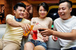 © DragonImages - Group of happy friends toasting with bottles of fruit juice while having fun at a party