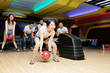 © DragonImages - Young woman throwing ball while playing bowling together with her friends