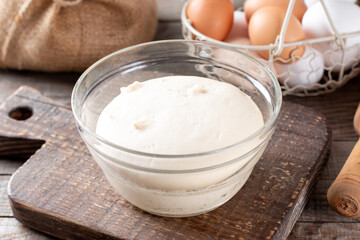 Wall Mural - Rising Yeast Dough inglass bowl close up and fresh yeast