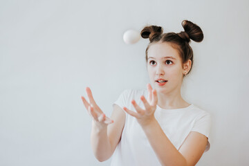 A cute happy teenage girl with bunny ears made of her hair holding white eggs in her hands. Kid ready for Easter hunt party, going to paint eggs. Happy Easter, holiday, childhood concept.