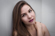 © Lyubov K - A beautiful fair-skinned woman. Portrait of a face of a young woman with clean healthy skin on a light background. Makeup with bright lips. Mysterious look. Straight brown hair. brunette with bright c