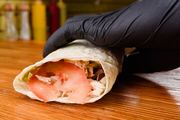 Wall Mural - Burrito making process. The chef wraps stuffed pita on a wooden table. Mexican dish.