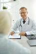 © Kostiantyn - Joyful male doctor talking with senior woman in his office