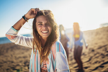 Happy young woman on the beach with her friends in background. Group of friends enjoying on beach holiday.