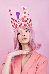 Wall Mural - Portrait of a sexy young woman with pink hair, Crown of hearts on the head. Perfect hairstyle and hair coloring. Girl with beautiful eyes and long pink hair