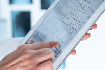 doctor is filling out a patient registration form on a digital tablet.