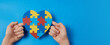 Autistic boy hands holding jigsaw puzzle heart shape. Autism spectrum disorder family support concept. World Autism Awareness Day
