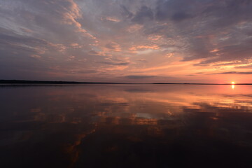 Wall Mural - sun setting on the horizon above the water surface lake