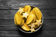 Delicious carambola fruits on black wooden table, top view