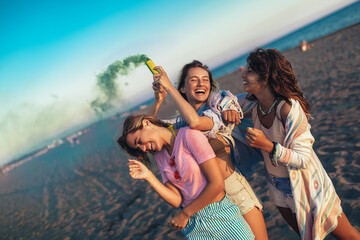 Wall Mural - Group of happy friend walking on beautiful beach in summer sunset in their hands is smoke fontain