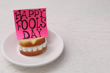 Wall Mural - Words Happy Fool's Day and sandwich of apple slices with marshmallows on wooden table. Space for text