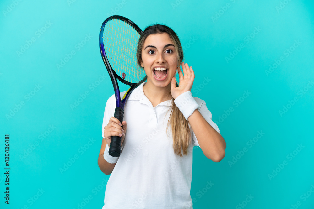 Young woman tennis player isolated on blue background with surprise and shocked facial expression - obrazy, fototapety, plakaty 