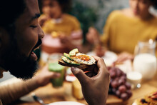 Close-up Of Black  Man Eating Healthy Sandwich At Home.
