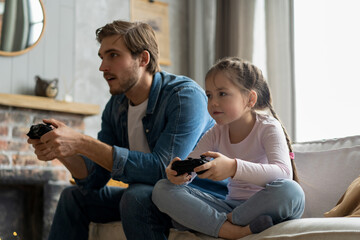 Wall Mural - family, gaming and entertainment concept - happy father and little daughter with gamepads playing video game at home.