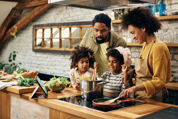 Happy black family enjoying in cooking together in the kitchen.