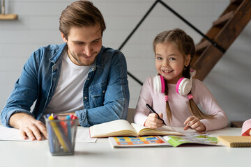 A father helping his little daughter to do her homework for the school