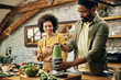 © Drazen - African American couple preparing green smoothie in the kitchen.