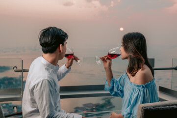 Wall Mural - Asian couple drinking wine having romantic  view in table at restaurant hotel.Vacation,Dinner,Love couple and sweet couple concept.