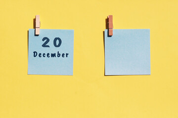 20 December. 20th day of the month, calendar date. Two blue sheets for writing on a yellow background. Top view, copy space. Winter month, day of the year concept