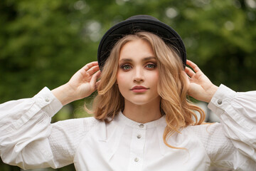 Wall Mural - cheerful woman with blonde hair wearing black hat outdoor