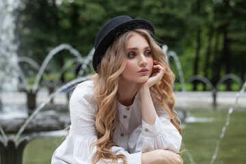 Wall Mural - blonde woman in black hat resting in park