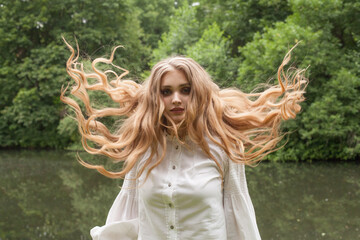 Canvas Print - Beautiful woman with long healthy blonde hair outdoor on foliage background