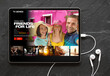 © Kaspars Grinvalds - Tablet computer with earphones on black background showing movie and TV shows online streaming service app on the screen