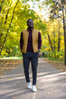 © satura_ - Positive african american young man in stylish clothes walks in late summer park on sunny warm warm day. Outdoor activity concept.