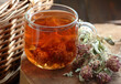 Red clover tea in glass cup on wood on rustic background of wicker, herbal drink is good for menopause, bone, heart health and for skin and hair care, closeup, naturopathy concept