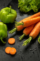 Wall Mural - Carrots and vegetables on black background in studio