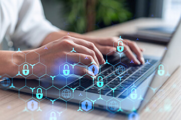 A woman programmer is typing a code on computer to protect a cyber security from hacker attacks and save clients confidential data. Padlock Hologram icons over the typing hands. Formal wear.