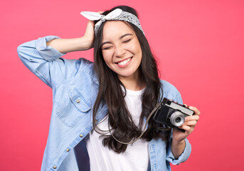 Cheerful gorgeous young Asian girl holding an old camera in her hands.