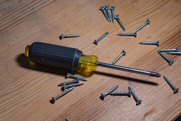 Screwdriver on a wooden top scrounged with screws