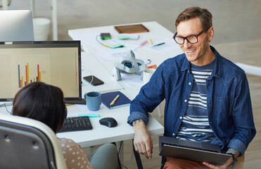 smiling project manager talking to female employee in office