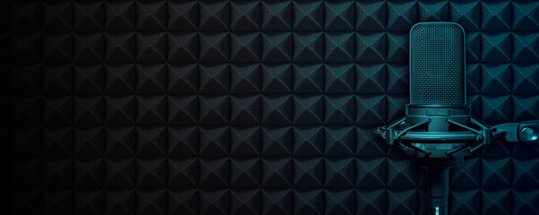 recording studio microphone on black acoustic foam background with blue light and copy space