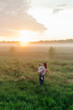 © Sergey Narevskih/Stocksy - Mother and child standing in misty field during sunset