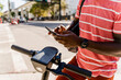 © Mauro Grigollo Photographer/Stocksy - Black man unlocking an electric scooter to move faster
