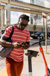 © Mauro Grigollo Photographer/Stocksy - Black man unlocking an electric scooter to move faster